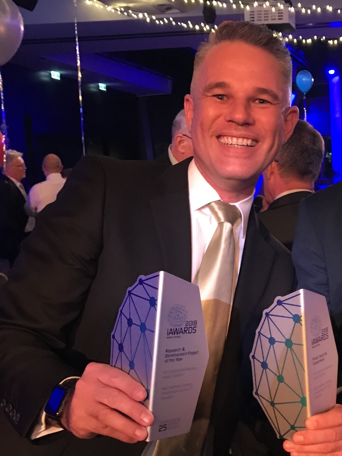 Benjamin Smith holding iAwards trophies for the Music Solution recognition.
